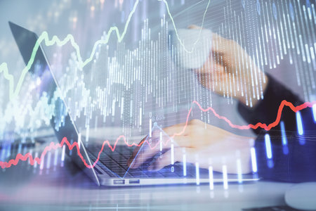 Double exposure of businesswoman hands typing on computer and forex graph hologram drawing....