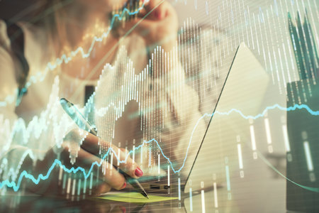 Double exposure of woman hands typing on computer and financial graph hologram drawing. Stock market...
