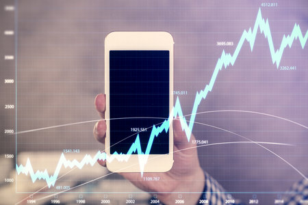 Double exposure of mans hands holding and using a digital device and forex graph drawing. Financial market concept.の写真素材