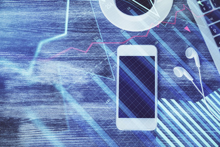 Double exposure of forex chart hologram over desktop with phone. Top view. Mobile trade platform concept.の写真素材
