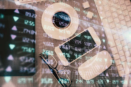 Multi exposure of forex graph hologram over desktop with phone. Top view. Mobile trade platform...