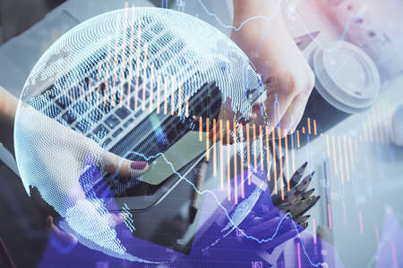 Double exposure of businesswoman hands typing on computer and financial graph hologram drawing....