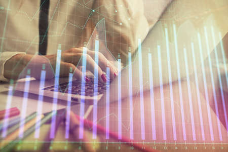 Double exposure of woman hands typing on computer and financial graph hologram drawing. Stock market analysis concept.の写真素材