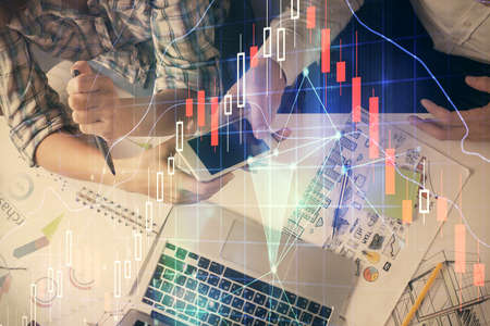Double exposure of forex graph drawing and man and woman working together holding and using a mobile...