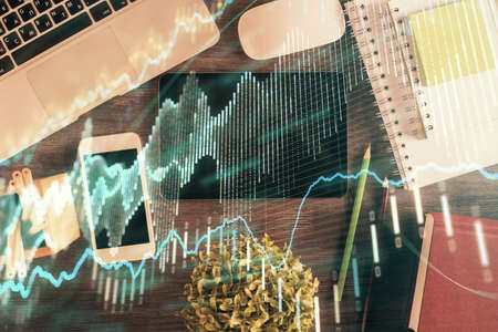 Double exposure of forex chart hologram over desktop with phone. Top view. Mobile trade platform...