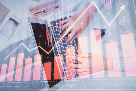 Double exposure of woman hands working on computer and forex graph hologram drawing. Top View....