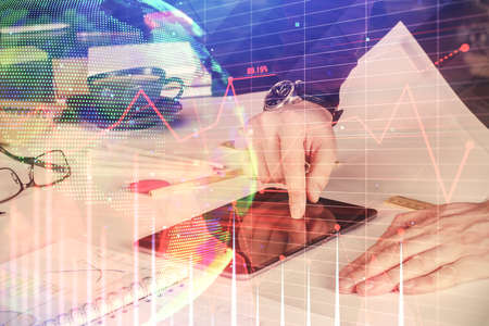 Double exposure of mans hands holding and using a digital device and forex graph drawing. Financial...