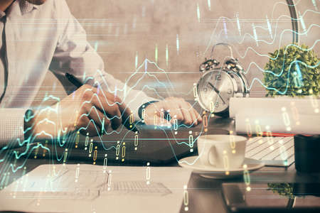 Double exposure of mans hands holding and using a phone and financial graph drawing. Analysis concept.の写真素材