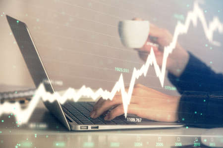 Double exposure of businesswoman hands typing on computer and forex graph hologram drawing....