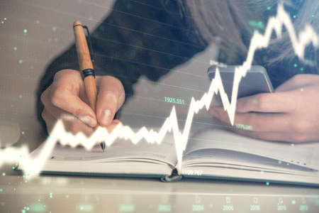 Double exposure of businesswoman hands typing on computer and forex graph hologram drawing....