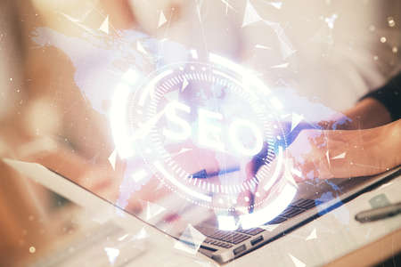 Double exposure of woman hands working on computer and seo hologram drawing. internet search...
