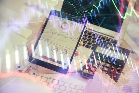 Double exposure of mans hands holding and using a digital device and forex graph drawing. Financial...