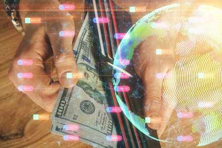 Double exposure of world map drawing hologram and us dollars bills and man hands.