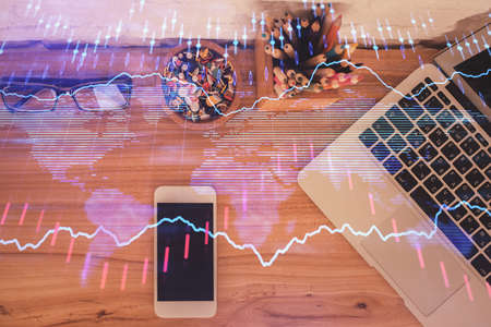 Double exposure of financial graph hologram over desktop with phone. Top view. Mobile trade platform concept.の写真素材
