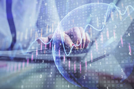 Double exposure of businesswoman hands typing on computer and financial graph hologram drawing....