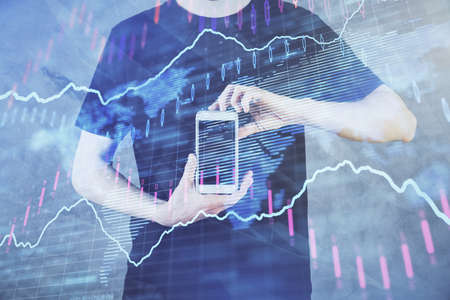Double exposure of mans hands holding and using a digital device and forex graph drawing. Financial...