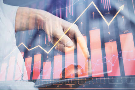 Double exposure of mans hands holding and using a digital device and forex graph drawing. Financial...