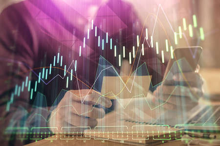 Double exposure of mans hands holding and using a phone and financial graph drawing. Analysis concept.の写真素材