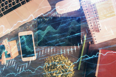 Double exposure of forex chart hologram over desktop with phone. Top view. Mobile trade platform...