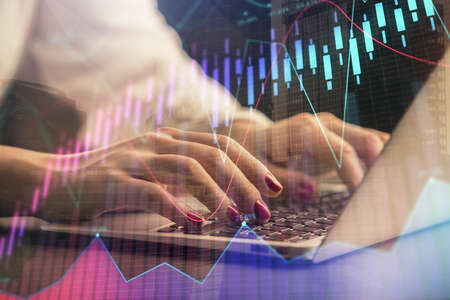 Double exposure of businesswoman hands typing on computer and forex chart hologram drawing....