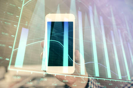 Double exposure of mans hands holding and using a digital device and forex graph drawing. Financial market concept.の写真素材