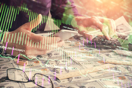 Double exposure of mans hands holding and using a digital device and forex graph drawing. Financial market concept.の写真素材