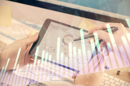 Double exposure of mans hands holding and using a phone and financial chart drawing. Market analysis...