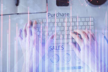 Double exposure of mans hands typing over laptop keyboard and forex chart hologram drawing. Top...