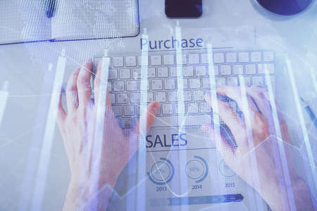 Double exposure of mans hands typing over laptop keyboard and forex chart hologram drawing. Top...