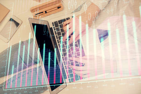 Double exposure of woman hands working on computer and forex graph hologram drawing. Top View....