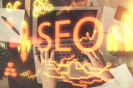 Double exposure of woman hands working on computer and seo hologram drawing. internet search...