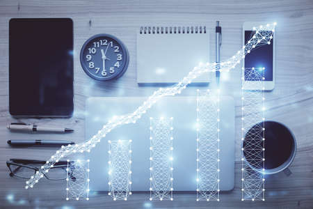 Double exposure of forex graph hologram over desktop with phone. Top view. Mobile trade platform...