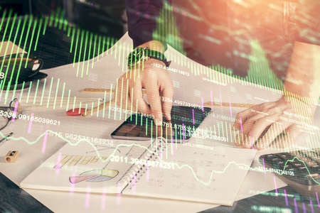Double exposure of mans hands holding and using a digital device and forex graph drawing. Financial...