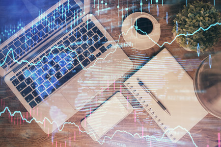Financial market graph and top view computer on the desktop background. Double exposure. Investment concept.の写真素材