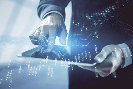 Double exposure of mans hands holding and using a digital device and forex graph drawing. Financial...