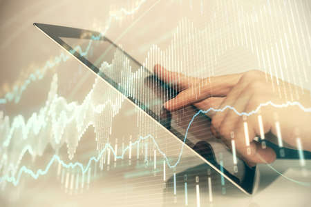 Multi exposure of mans hands holding and using a digital phone and forex graph drawing. Financial...