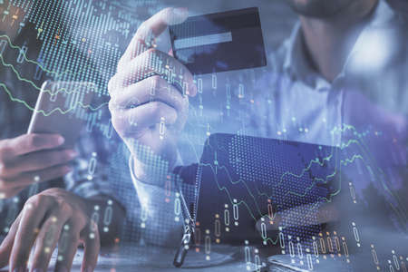 Double exposure of man and woman on-line shopping holding a credit card and forex graph hologram drawing. Stock market E-commerce pay on-line concept.の写真素材