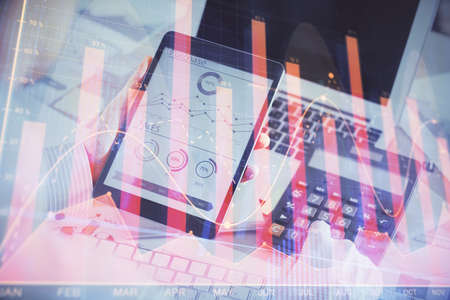 Double exposure of mans hands holding and using a digital device and forex graph drawing. Financial...