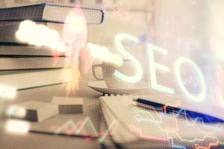 Double exposure of SEO writing and desktop with coffee and items on table background. Concept of search optimization.の写真素材