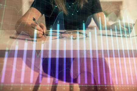 Double exposure of businesswoman hands typing on computer and forex chart hologram drawing....