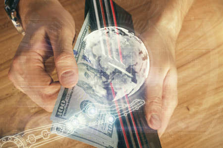Double exposure of world map drawing hologram and us dollars bills and man hands.の写真素材