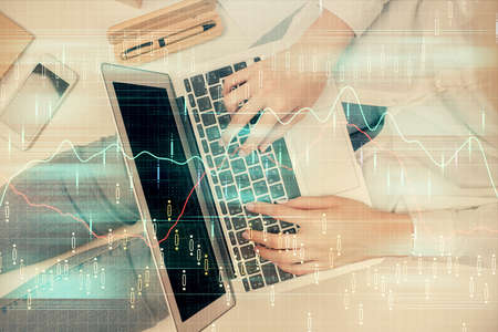 Double exposure of woman hands working on computer and forex graph hologram drawing. Top View....
