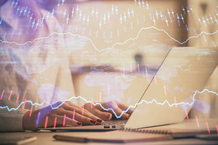 Double exposure of woman hands working on computer and forex graph hologram drawing. Financial...