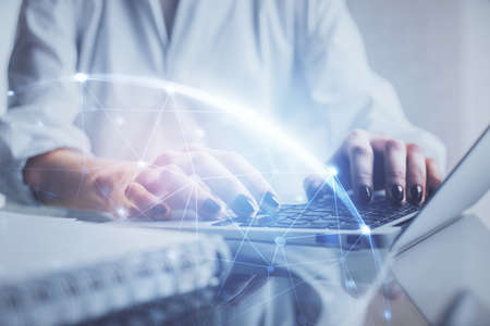 Double exposure of woman hands typing on computer and social network theme hologram drawing. People...