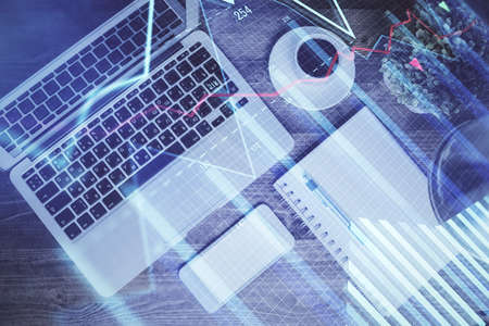 Financial market graph and top view computer on the desktop background. Double exposure. Investment...