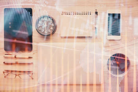 Double exposure of forex graph hologram over desktop with phone. Top view. Mobile trade platform...