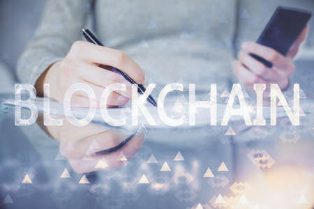Double exposure of blockchain business sketch hologram and woman holding and using a mobile device.