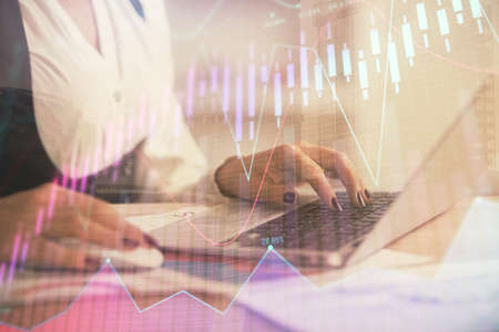 Double exposure of businesswoman hands typing on computer and forex graph hologram drawing....