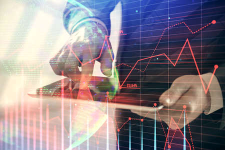 Double exposure of mans hands holding and using a digital device and forex graph drawing. Financial...