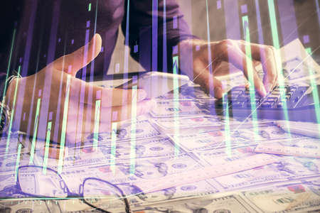 Double exposure of mans hands holding and using a digital device and forex graph drawing. Financial market concept.の写真素材